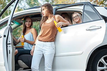 Image showing The young women in the car smiling and drinking juice