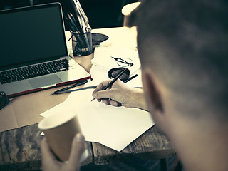 Image showing Vintage hipster wooden desktop side view, male hands with cup and holding a pencil