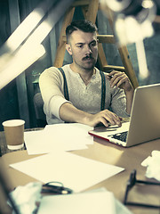 Image showing Portrait of a bearded businessman who is checking details of his upcoming meeting in his notebook and typing.