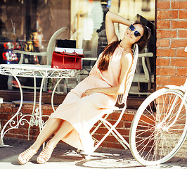 Image showing young pretty brunette woman after shopping sitting at cafe outside on street smiling