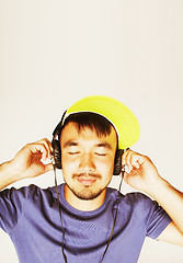 Image showing young asian man in hat and headphones listening music on white b