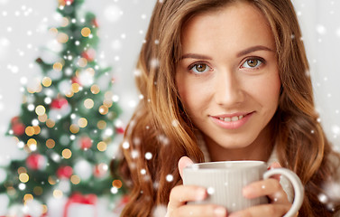 Image showing close up of woman with tea cup over christmas tree