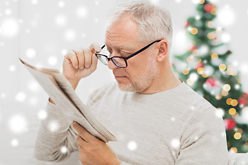 Image showing senior man in glasses reading newspaper at home