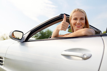 Image showing happy young woman in convertible car thumbs up