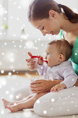 Image showing mother with spoon feeding little baby at home