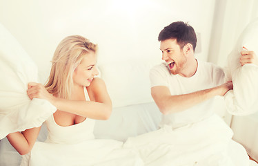 Image showing happy couple having pillow fight in bed at home