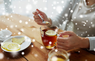 Image showing close up of woman adding honey to tea with lemon