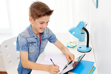 Image showing student boy with tablet pc writing to notebook