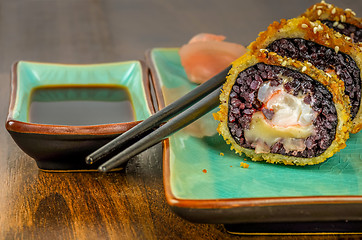 Image showing Black sushi rolls served on turquoise plate