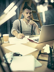 Image showing Portrait of a bearded businessman who is checking details of his upcoming meeting in his notebook and typing.