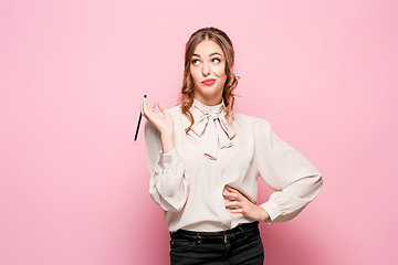 Image showing The serious frustrated young beautiful business woman on pink background