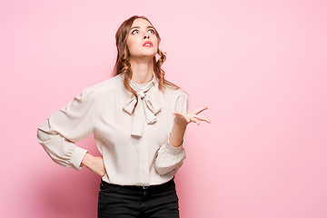 Image showing The serious frustrated young beautiful business woman on pink background