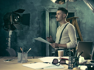 Image showing Portrait of a bearded businessman who is checking details of his upcoming meeting in his notebook and typing.