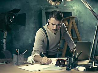 Image showing Portrait of a bearded businessman who is checking details of his upcoming meeting in his notebook and typing.