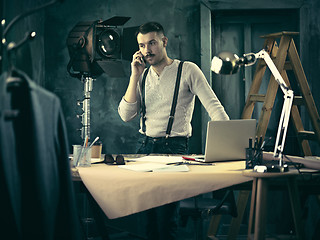 Image showing Portrait of a bearded businessman who is working with his notebook at loft studio.