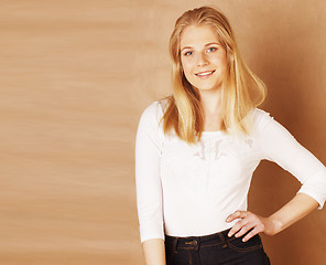 Image showing young pretty blond woman happy cheerful smiling closeup on warm brown background, lifestyle real people concept copyspace