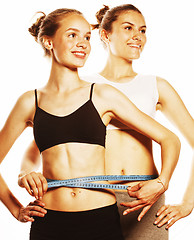 Image showing two sport girls measuring themselves isolated on white