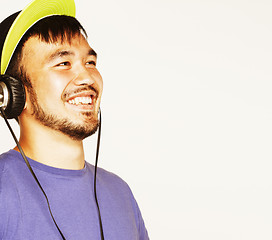 Image showing young asian man in hat and headphones listening music on white b