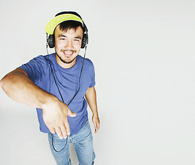 Image showing young asian man in hat and headphones listening music on white b