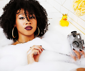 Image showing young afro-american teen girl laying in bath with foam, wearing 