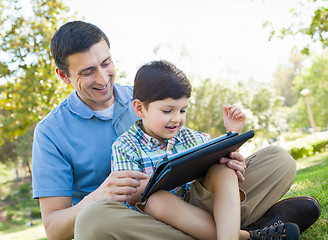 Image showing Happy Father and Son Playing on a Computer Tablet Outside.