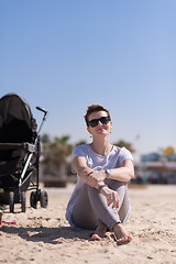 Image showing Young mother with sunglasses relaxing on beach