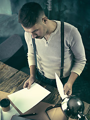 Image showing Portrait of a bearded businessman who is checking details of his upcoming meeting in his notebook and typing.