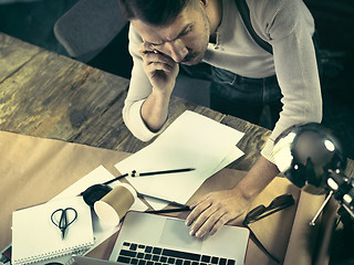 Image showing Portrait of a bearded businessman who is working with his notebook at loft studio.