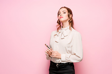 Image showing The serious frustrated young beautiful business woman on pink background