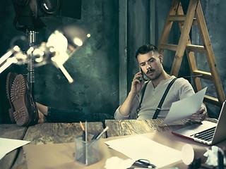 Image showing Portrait of a bearded businessman who is working with his notebook at loft studio.