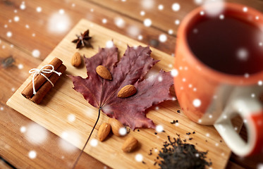 Image showing cup of tea, maple leaf and almond on wooden board