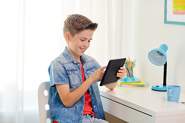 Image showing smiling boy with tablet pc sitting at home desk