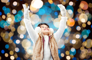 Image showing happy girl in winter earmuffs over holidays lights