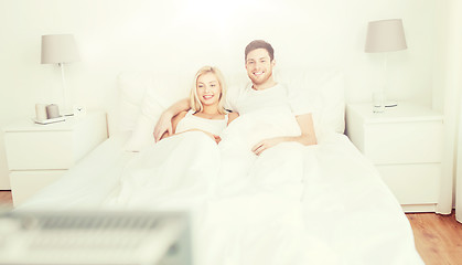 Image showing happy couple lying in bed at home and watching tv