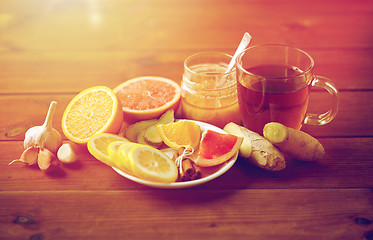 Image showing ginger tea with honey, citrus and garlic on wood