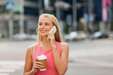 Image showing woman with coffee calling on smartphone in city