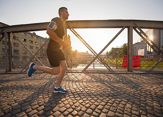 Image showing man jogging across the bridge at sunny morning