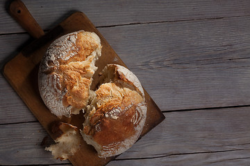 Image showing Torned homemade bread loaf on old cutting board with a free space on the right