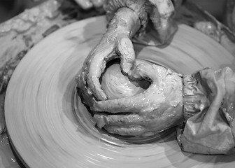Image showing Black and white hands of young girl in process of making clay bo