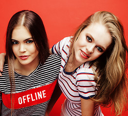 Image showing two best friends teenage girls together having fun, posing emotional on red background, besties happy smiling, lifestyle people concept close up