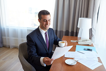 Image showing businessman with papers drinking coffee at hotel