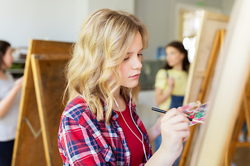 Image showing student girl with easel painting at art school