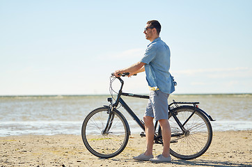 Image showing happy young man with bicycle on beach 