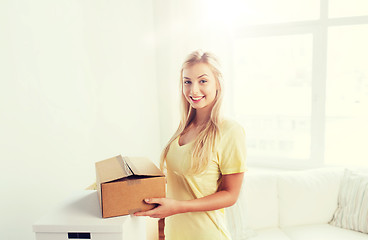 Image showing smiling young woman with cardboard box at home