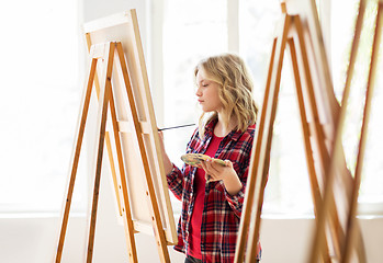 Image showing student girl with easel painting at art school