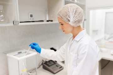 Image showing woman with sulphuric acid and scale at laboratory