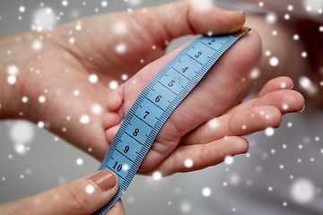 Image showing close up of hands with tape measuring baby foot