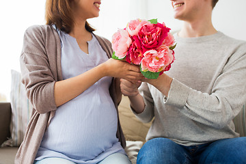 Image showing close up of man giving flowers to pregnant wife