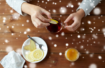 Image showing close up of ill woman adding lemon to tea cup