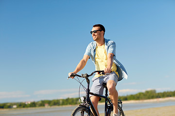 Image showing happy man riding bicycle along summer beach